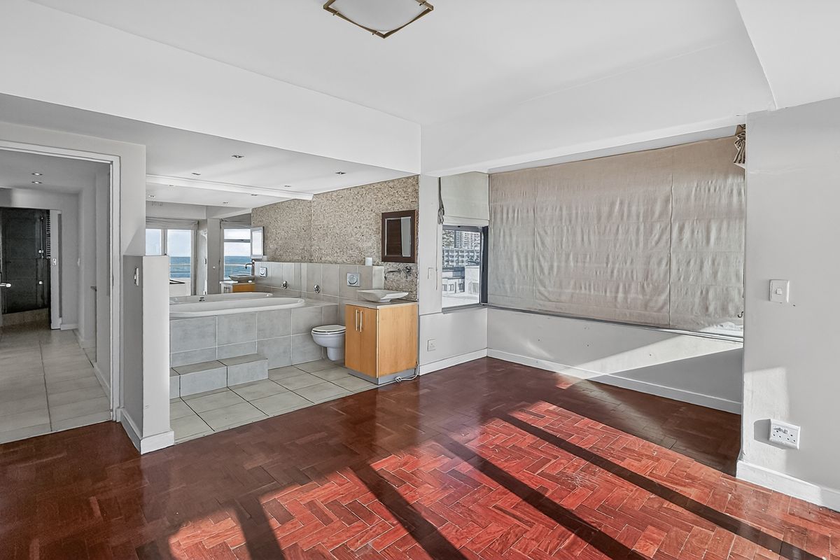 Open-plan bedroom featuring parquet flooring and an integrated en-suite bathroom with a built-in bathtub and vanity.