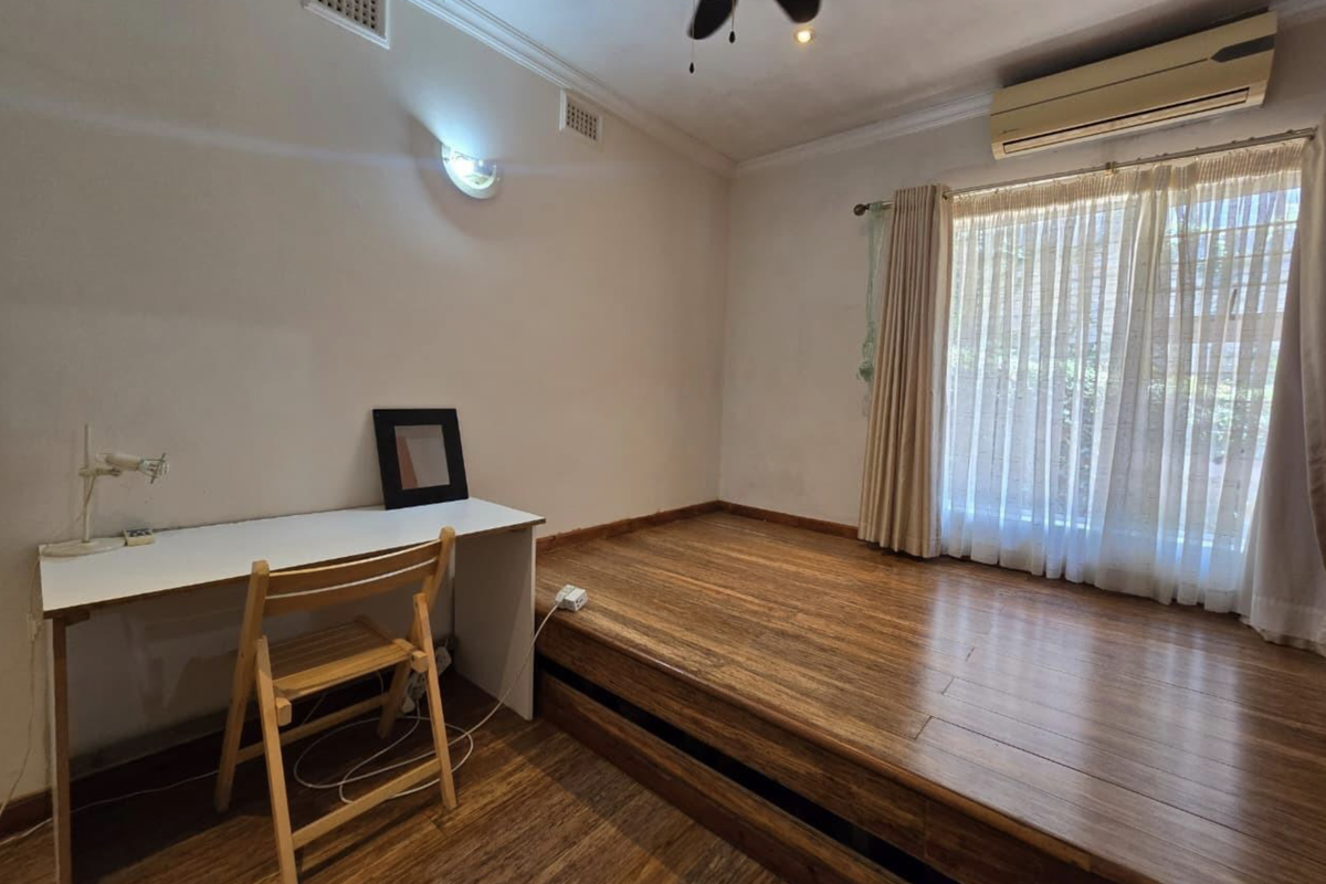 Bedroom featuring timber flooring, a raised platform area, ceiling fan, and wall-mounted air conditioning unit.
