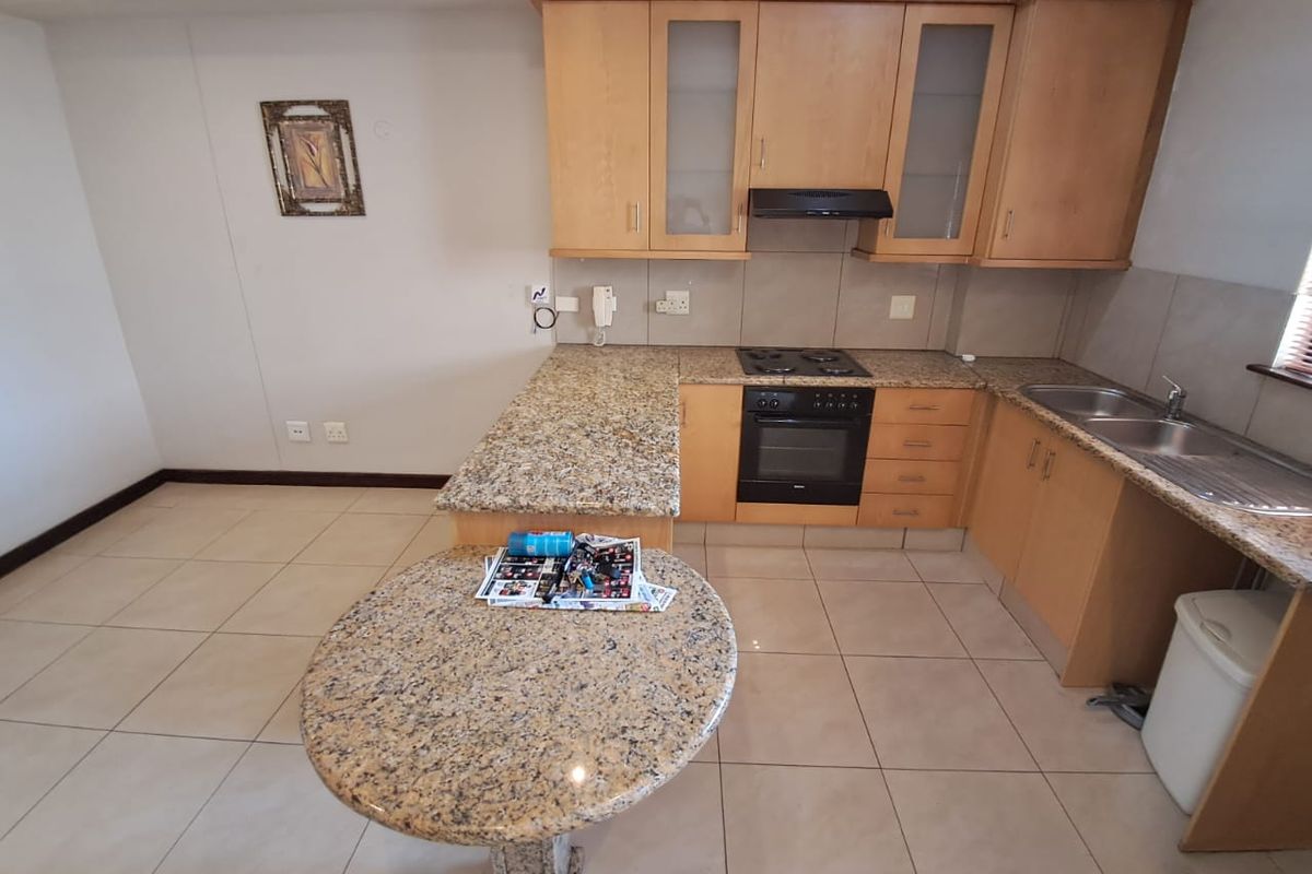 A functional kitchen featuring light wood cabinetry, granite countertops, a built-in oven, hob, extractor fan, and a breakfast nook extension.