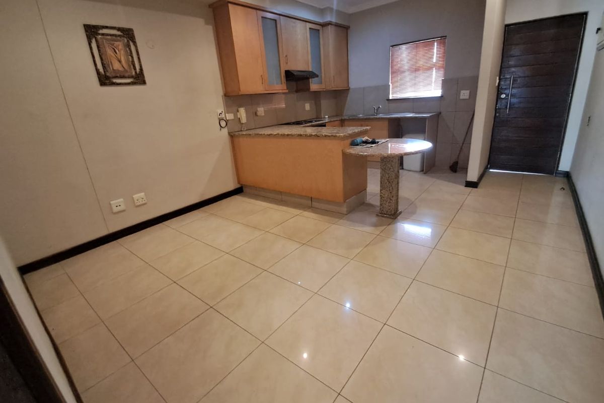 Open plan kitchen featuring light wood cabinetry, granite countertops, a breakfast bar, and tiled flooring, seamlessly integrated with the living area.