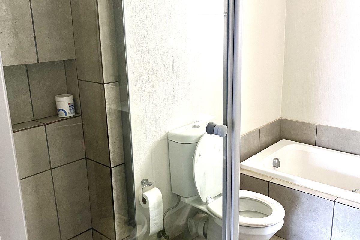 A functional bathroom featuring a tiled shower enclosure with glass door, a built-in bathtub, and a standard toilet.