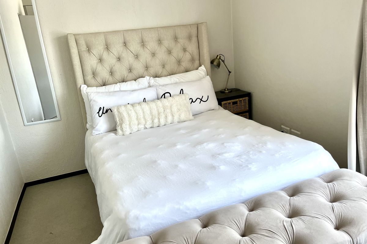 A well-lit bedroom featuring neutral wall finishes and carpeted flooring, providing a comfortable and functional sleeping space.