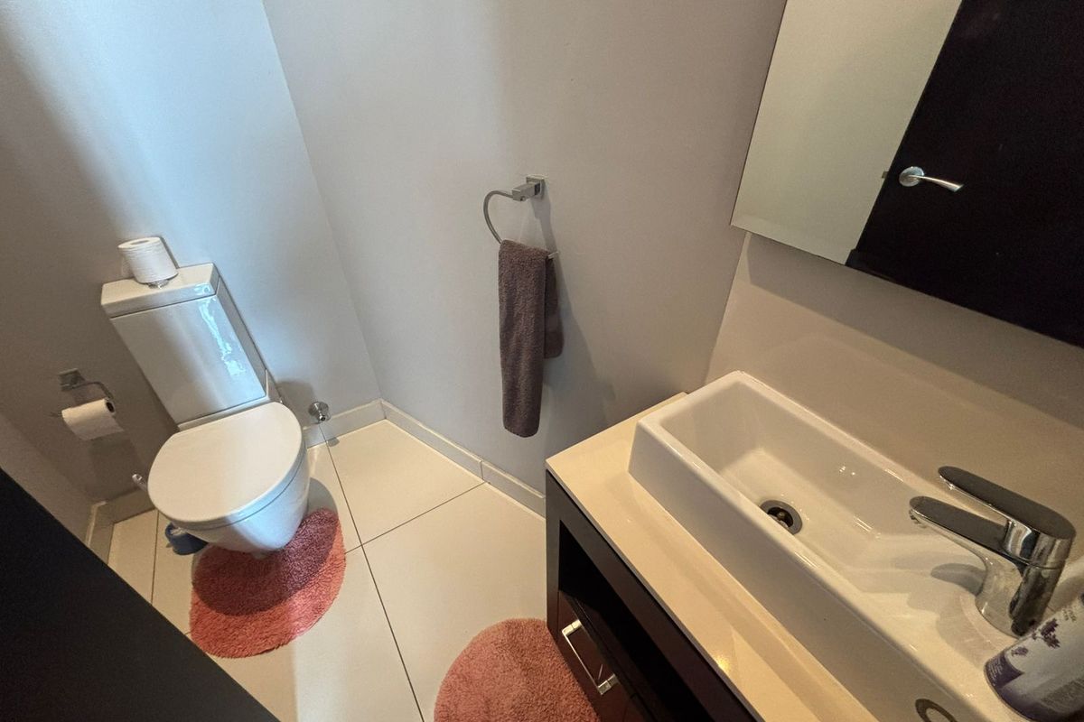 A modern bathroom featuring a sleek vessel sink vanity, a wall-mounted mirror, and a standard toilet with tiled flooring.