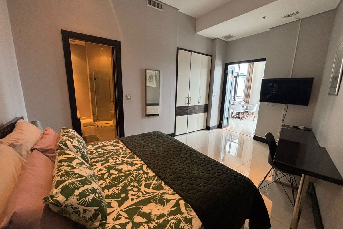 A well-maintained bedroom featuring tiled flooring, built-in wardrobes, recessed lighting, and an en-suite bathroom, with direct access to a balcony area.