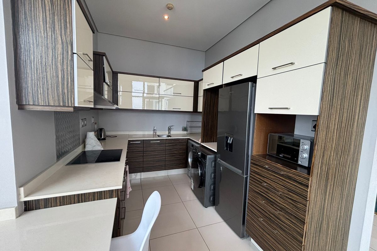 Modern kitchen featuring two-tone cabinetry, stone countertops, integrated appliances, and tiled flooring, offering a clean and functional workspace.