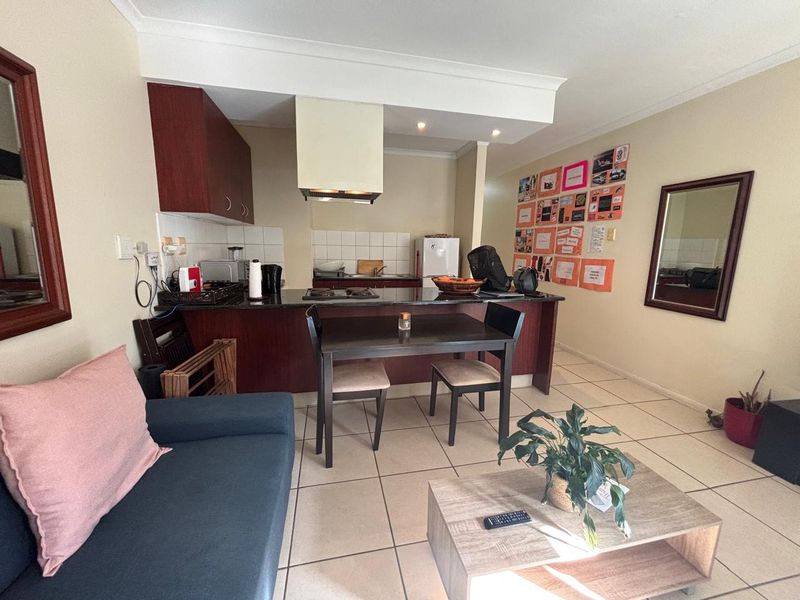 Open-plan living and kitchen area featuring tiled flooring, dark wood cabinetry, granite countertops, and a built-in hob with an extractor fan.