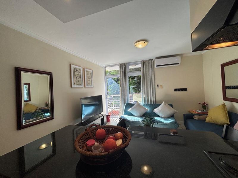 Open-plan living area featuring a modern kitchen with granite countertops, split-system air conditioning, and direct access to a private balcony.