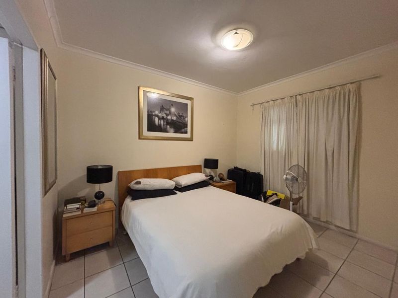 A standard bedroom featuring tiled flooring, neutral walls, and a ceiling light fixture, providing a functional and well-lit sleeping space.