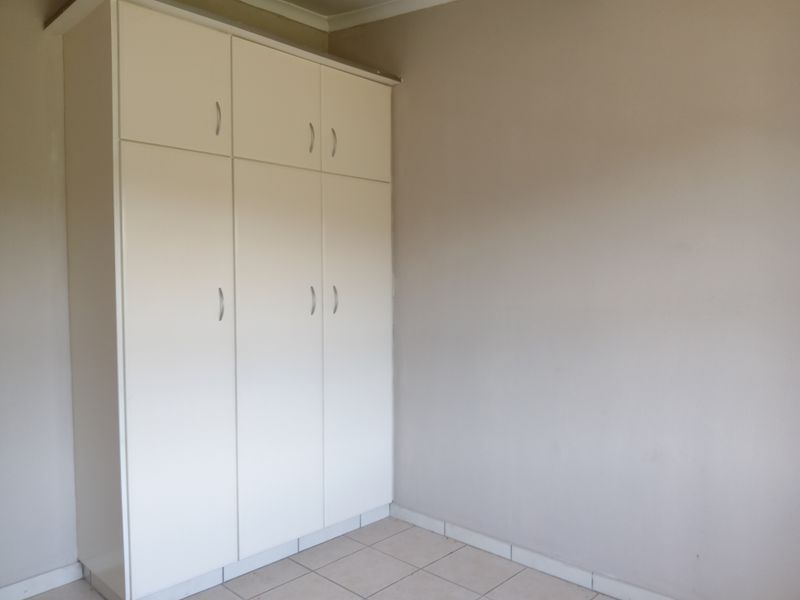 A bedroom featuring built-in floor-to-ceiling cupboards with white cabinetry and tiled flooring.