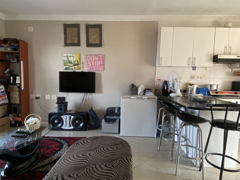 Open-plan living area featuring a kitchen with built-in cabinetry, extractor fan, and a breakfast counter, seamlessly connected to the lounge space.