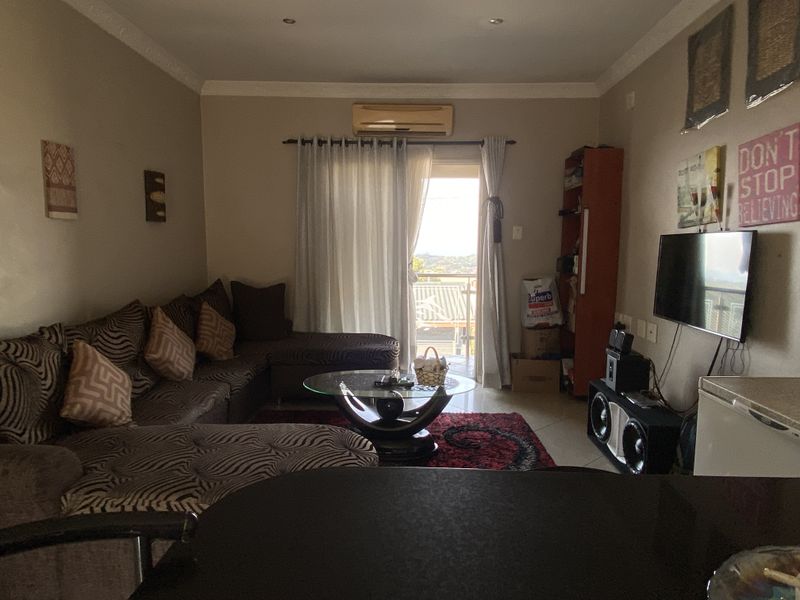 A living room featuring a split-system air conditioner, recessed downlights, and a sliding glass door providing access to an outdoor balcony area.