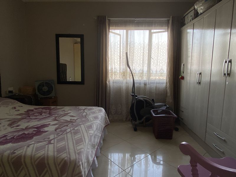 A bedroom featuring tiled flooring and built-in cupboards, offering a functional space with natural light from the window.