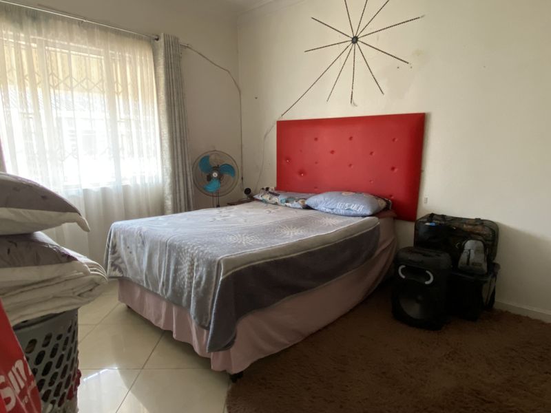 A bedroom featuring tiled flooring, a window with security bars, and neutral wall finishes.