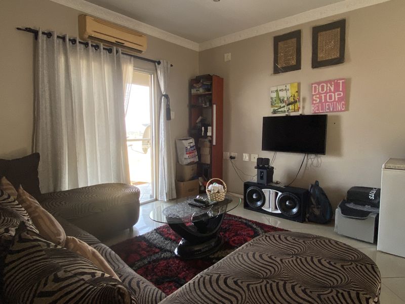 A living room featuring tiled flooring, coved ceilings, and a wall-mounted air conditioning unit with access to an outdoor balcony area.
