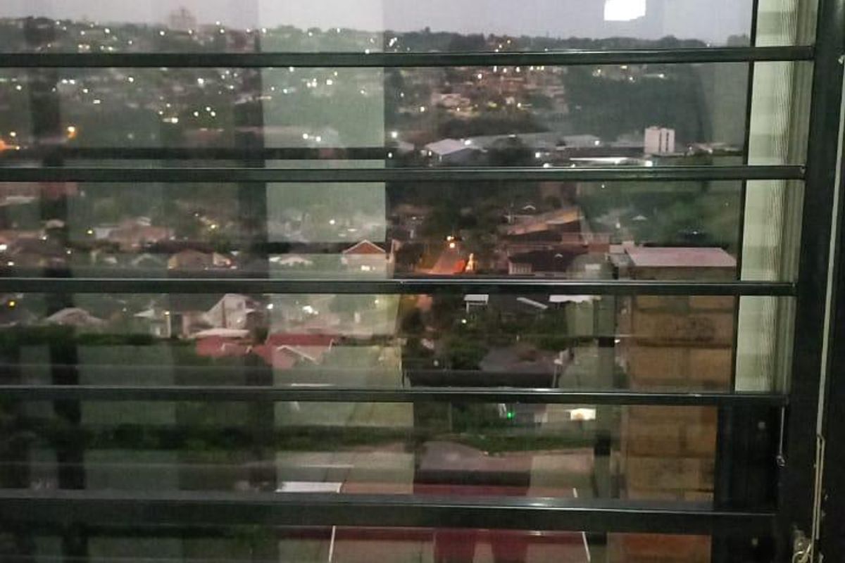 A view of the surrounding neighborhood at night, captured through a security gate from a tiled balcony area.