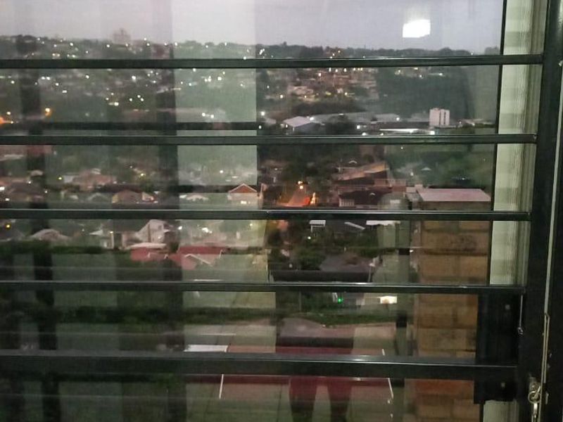 A view of the surrounding neighborhood at night, captured through a security gate from a tiled balcony area.