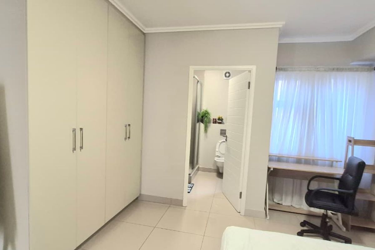 A bedroom featuring built-in cupboards, tiled flooring, and direct access to an en-suite bathroom.