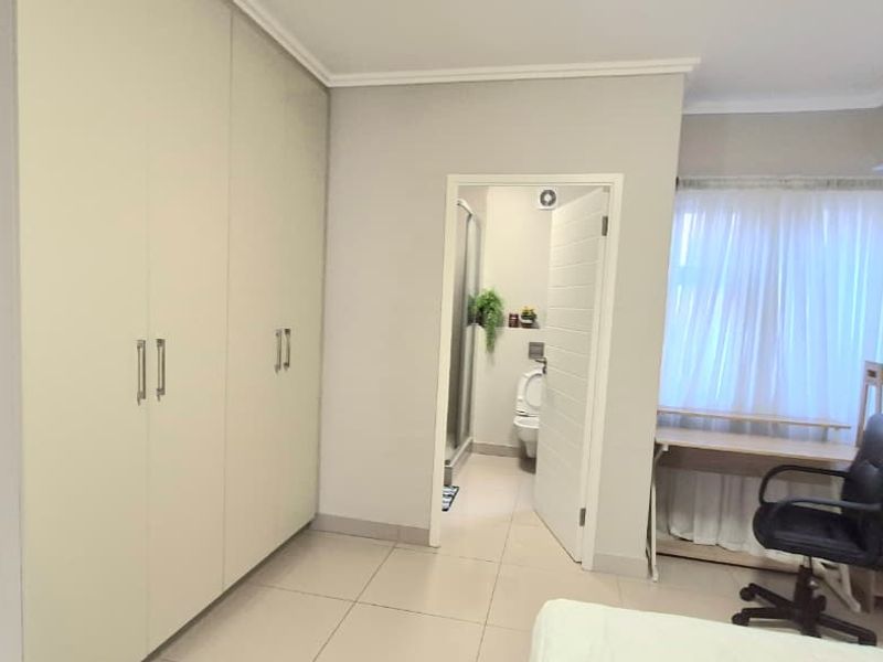 A bedroom featuring built-in cupboards, tiled flooring, and direct access to an en-suite bathroom.