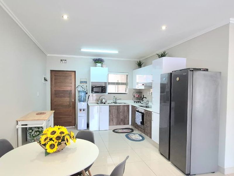 Open-plan kitchen and dining area featuring modern cabinetry, tiled flooring, and recessed lighting, creating a functional and bright living space.