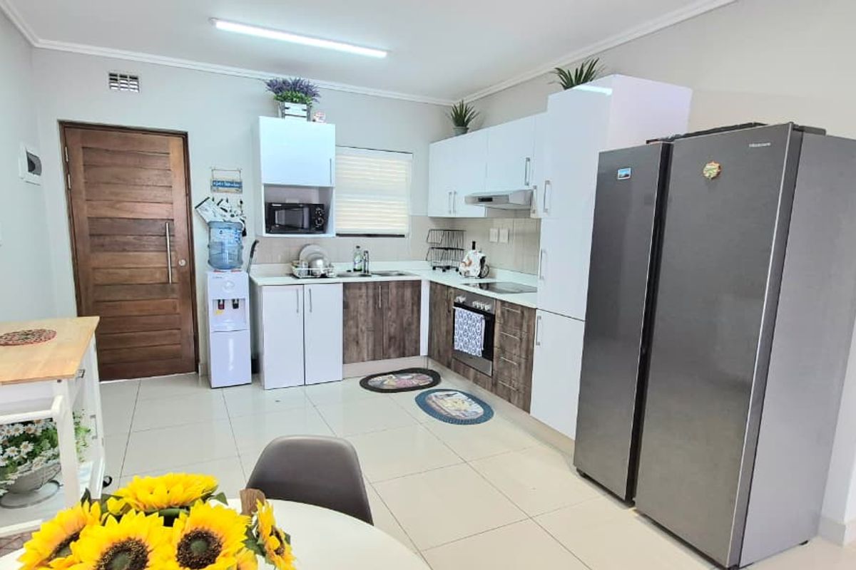 A functional kitchen featuring modern two-tone cabinetry, built-in oven and hob, extractor fan, and tiled flooring, providing a clean and practical cooking space.