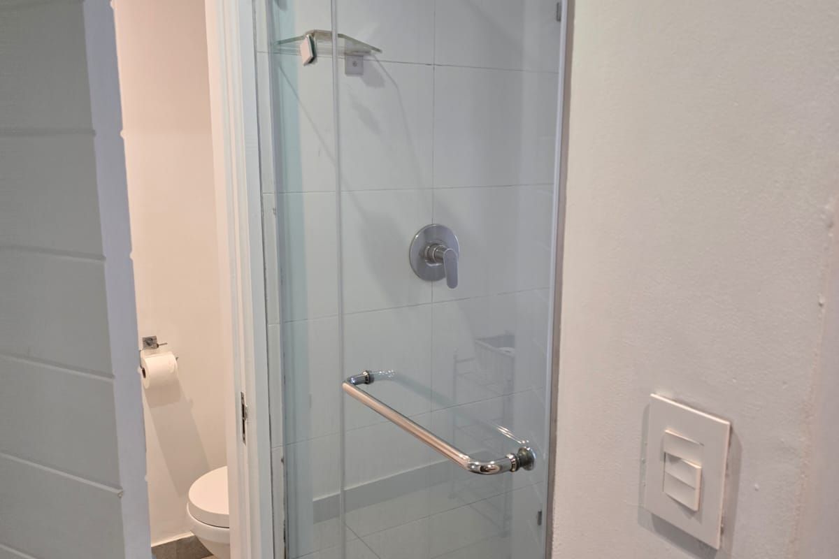A clean bathroom featuring a glass-enclosed shower with modern fixtures and a separate toilet area with tiled finishes.