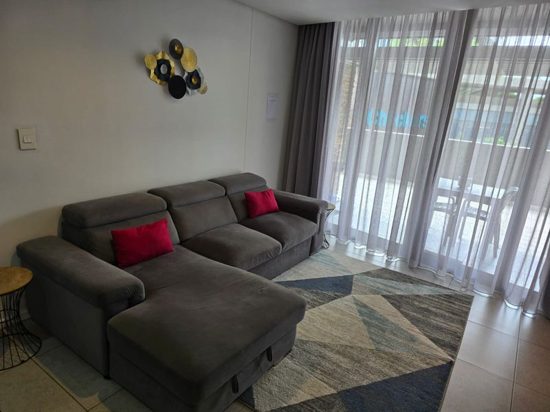 A comfortable living room featuring tiled flooring and large sliding glass doors that provide access to an outdoor patio area.