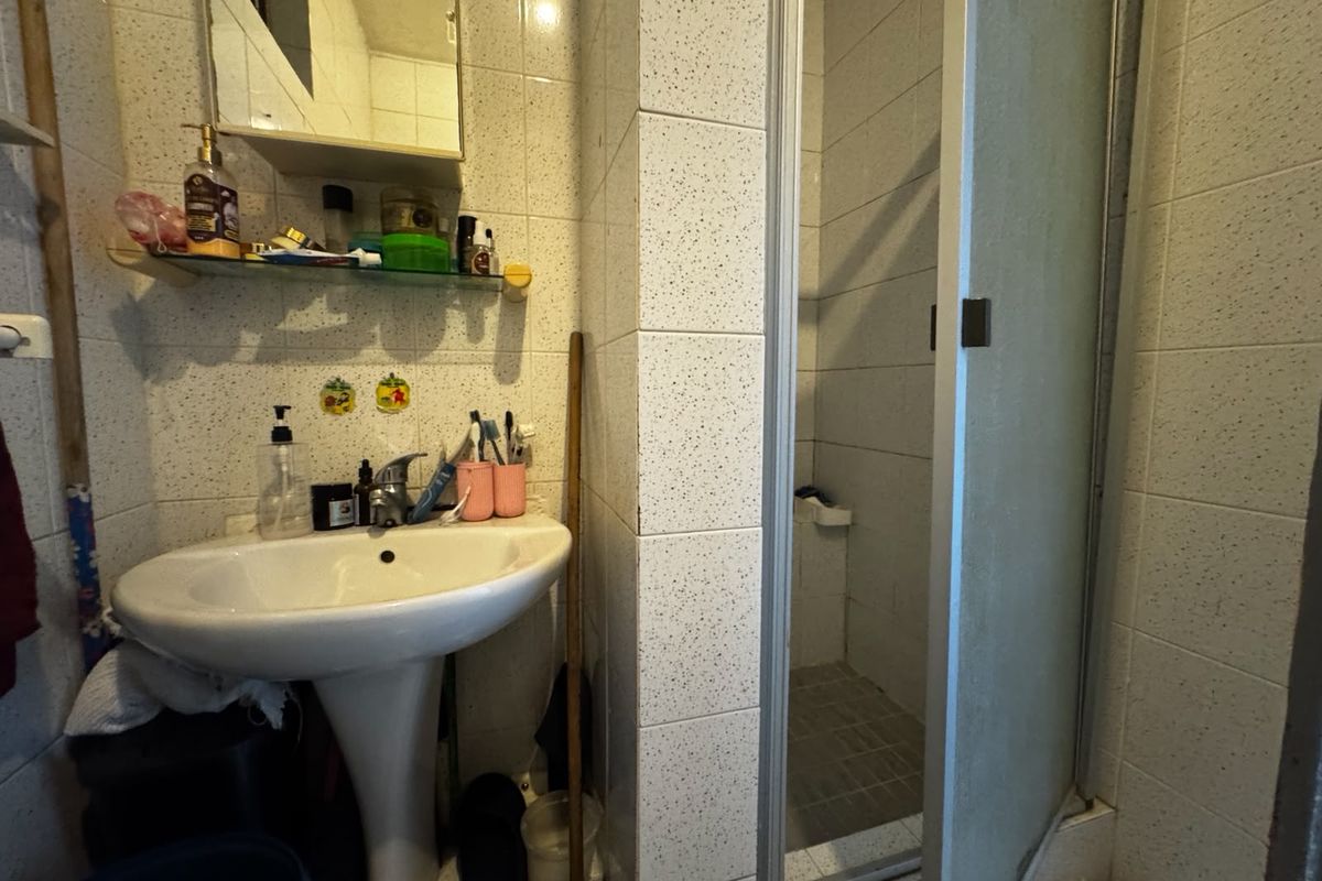 Compact bathroom featuring a pedestal sink, medicine cabinet, and a separate shower enclosure with tiled finishes throughout.