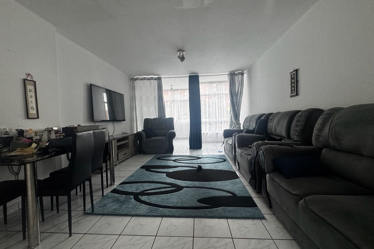A living room featuring tiled flooring and a large sliding glass door providing natural light.