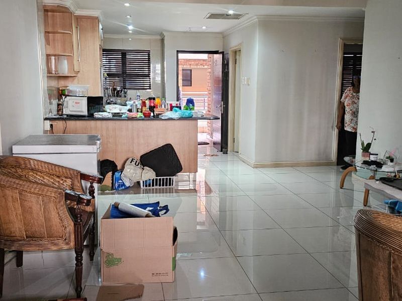 Open-plan living and kitchen area featuring tiled flooring, granite countertops, and built-in cabinetry, offering a functional layout for modern apartment living.