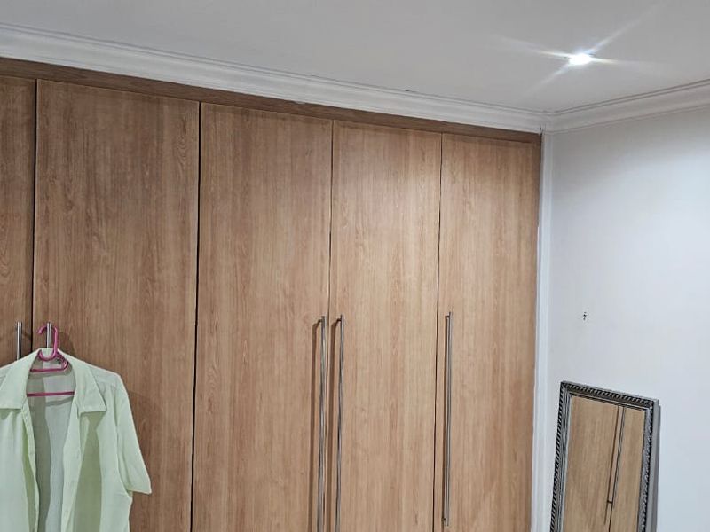 Bedroom featuring floor-to-ceiling wood-finish built-in cupboards, crown molding, and recessed ceiling lighting.