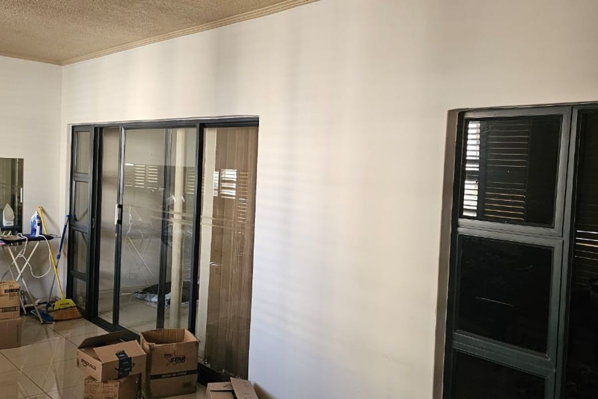 Spacious living area featuring large sliding glass doors, tiled flooring, and neutral walls, offering a bright and versatile space for modern living.