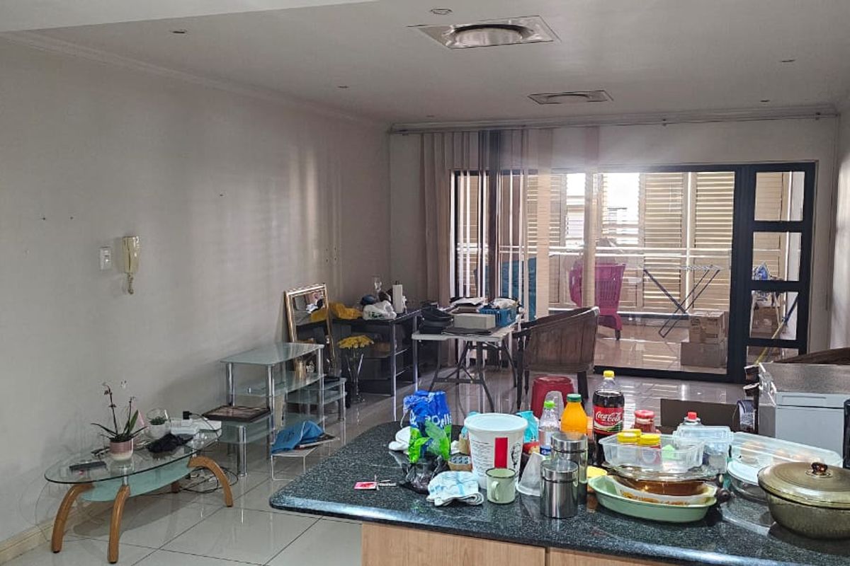 Open plan living and kitchen area featuring tiled floors, granite countertops, and large sliding doors leading to a balcony.