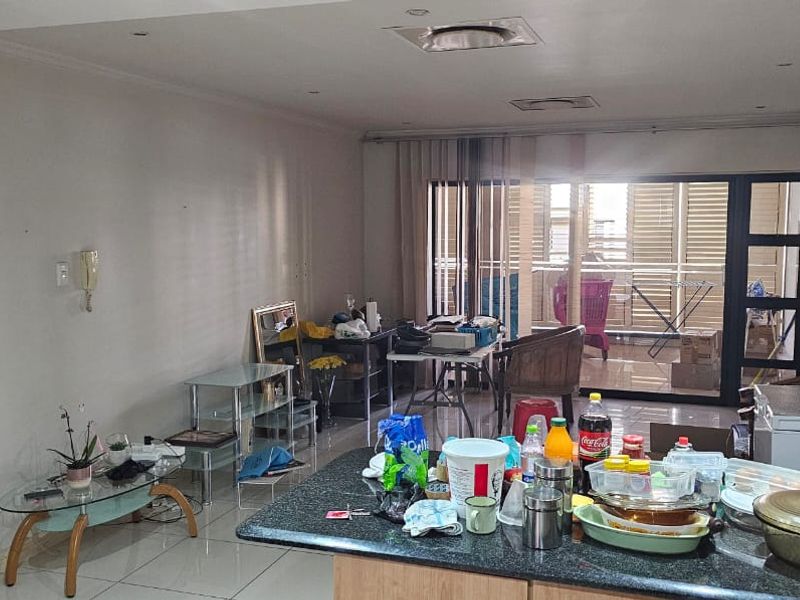 Open plan living and kitchen area featuring tiled floors, granite countertops, and large sliding doors leading to a balcony.