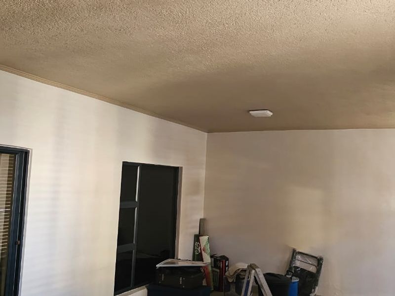 A covered patio or balcony area featuring sliding glass doors, a fixed window, and a textured ceiling with a central light fixture.