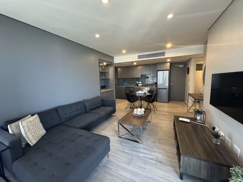 Modern open-plan living area featuring tiled flooring, recessed lighting, ducted air conditioning, and a sleek, well-appointed kitchen with integrated cabinetry.