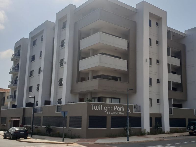 Exterior view of Twilight Park apartment complex, featuring modern multi-story architecture with balconies and secure perimeter walling.