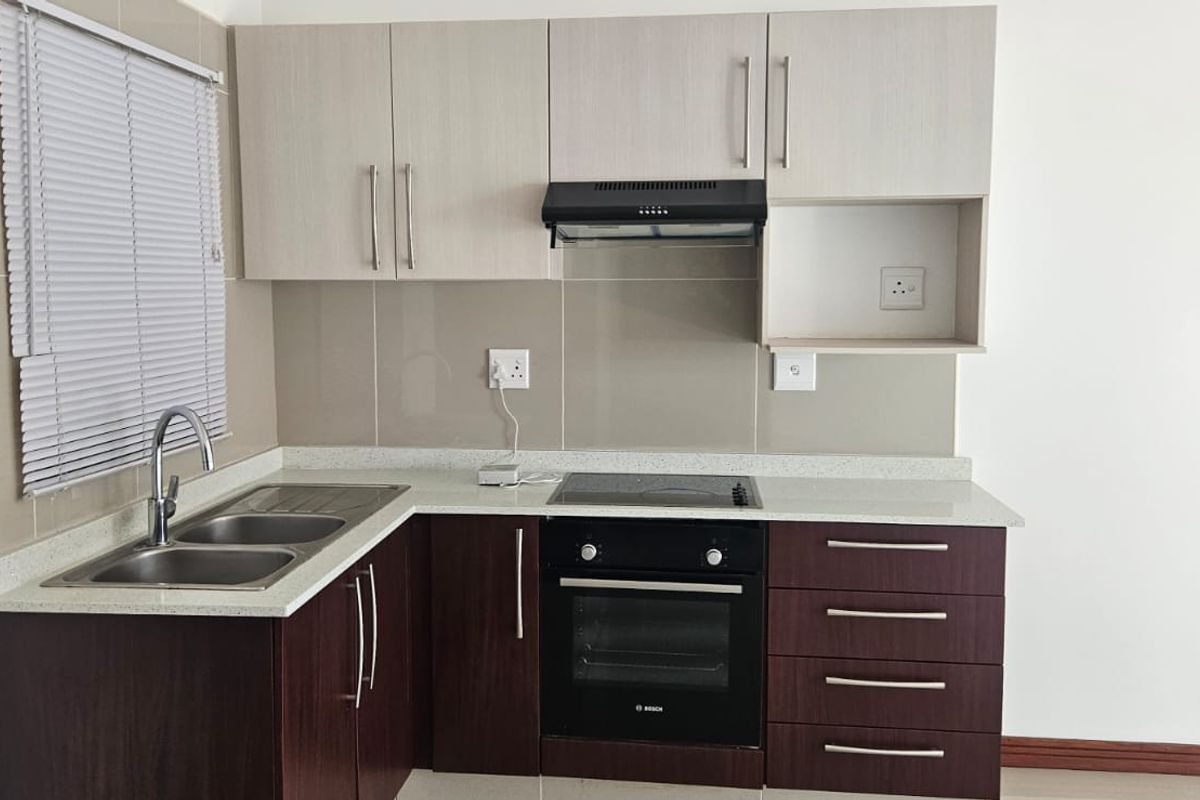 Modern kitchen featuring dark wood lower cabinets, light upper cabinetry, stone countertops, integrated oven, hob, extractor fan, and a double bowl sink.