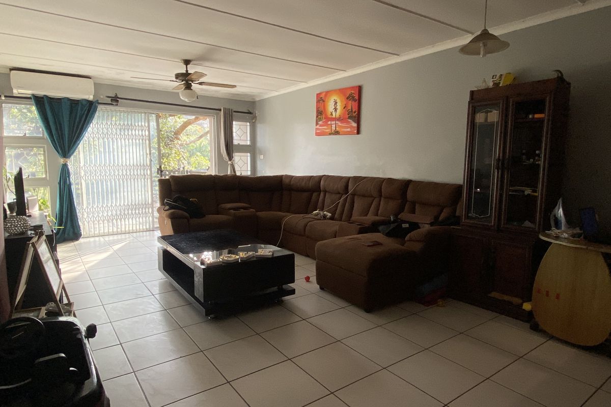 Spacious living room featuring tiled flooring, a ceiling fan, split-system air conditioning, and large sliding glass doors leading to an outdoor area.