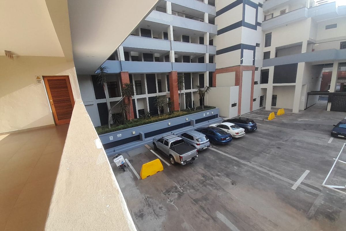 View of the apartment complex rear parking area and building facade from an elevated balcony.