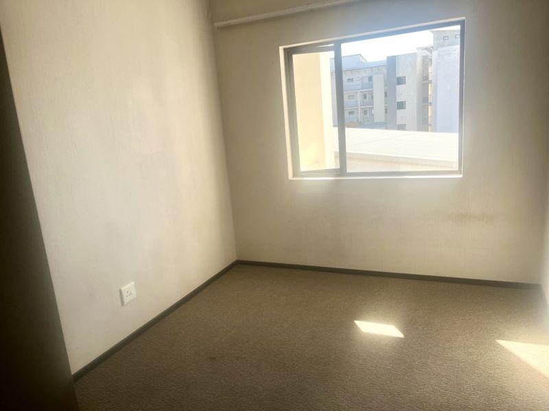 An empty bedroom featuring carpet flooring and a sliding window, requiring cosmetic updates to the walls and flooring to improve its overall condition.