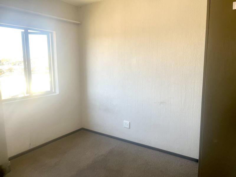 An empty bedroom featuring neutral walls, carpeted flooring, and a built-in cupboard, offering a blank canvas for personalization.