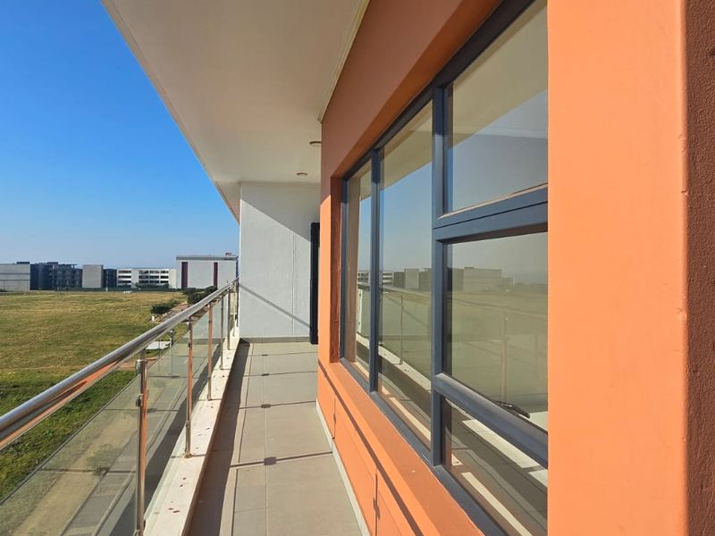 A spacious balcony featuring a modern glass balustrade with stainless steel railings, offering expansive views over the surrounding landscape.