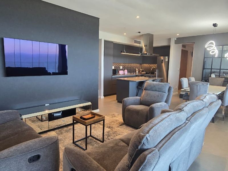 Modern open-plan living area featuring a sleek kitchen with island, recessed lighting, and contemporary finishes throughout the spacious, well-maintained interior.