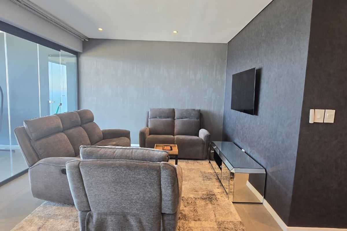 Modern living room featuring a textured feature wall, recessed downlighting, and large sliding glass doors leading to an outdoor balcony area.