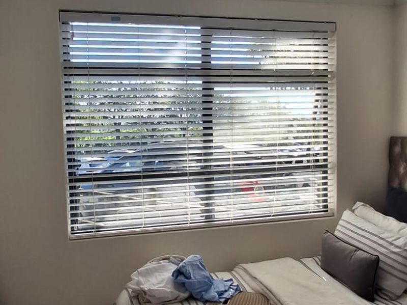 A bedroom featuring a window with venetian blinds and a flush mount ceiling light fixture.