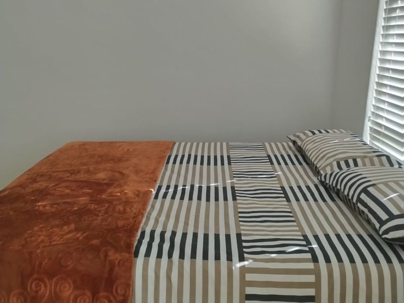 A well-lit bedroom featuring neutral wall finishes and fitted venetian blinds, providing a clean and functional living space.