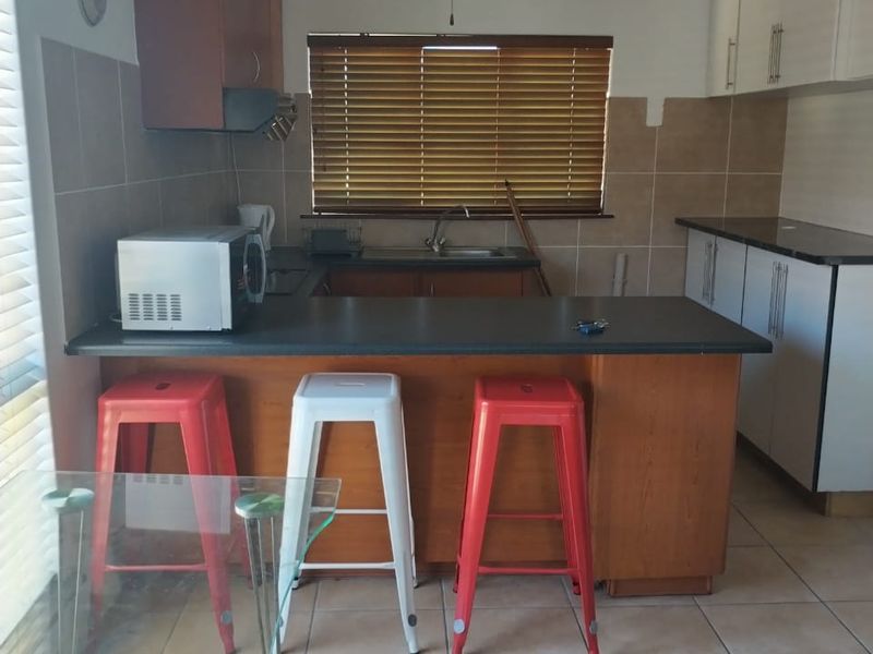 Functional kitchen featuring a breakfast bar, laminate countertops, tiled backsplash, and a mix of wood-tone and white cabinetry.