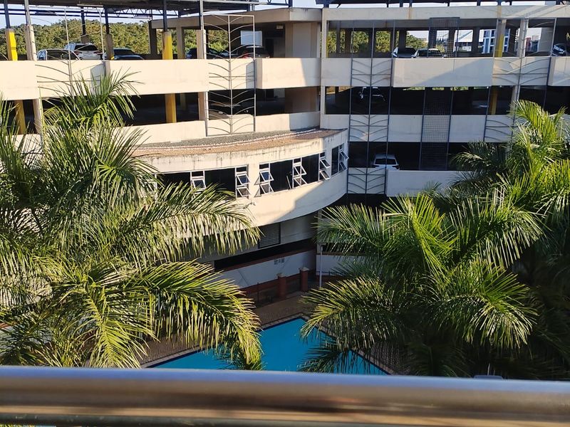 View of a swimming pool area situated within a multi-level apartment complex with an integrated parking structure.