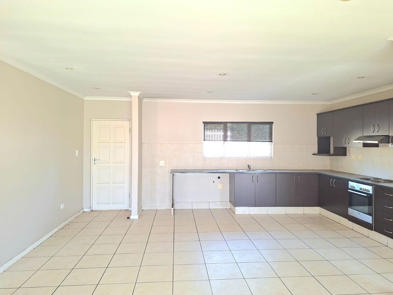 Spacious open-plan kitchen featuring dark cabinetry, built-in oven, extractor fan, tiled flooring, and a neutral color palette, ready for personalization.