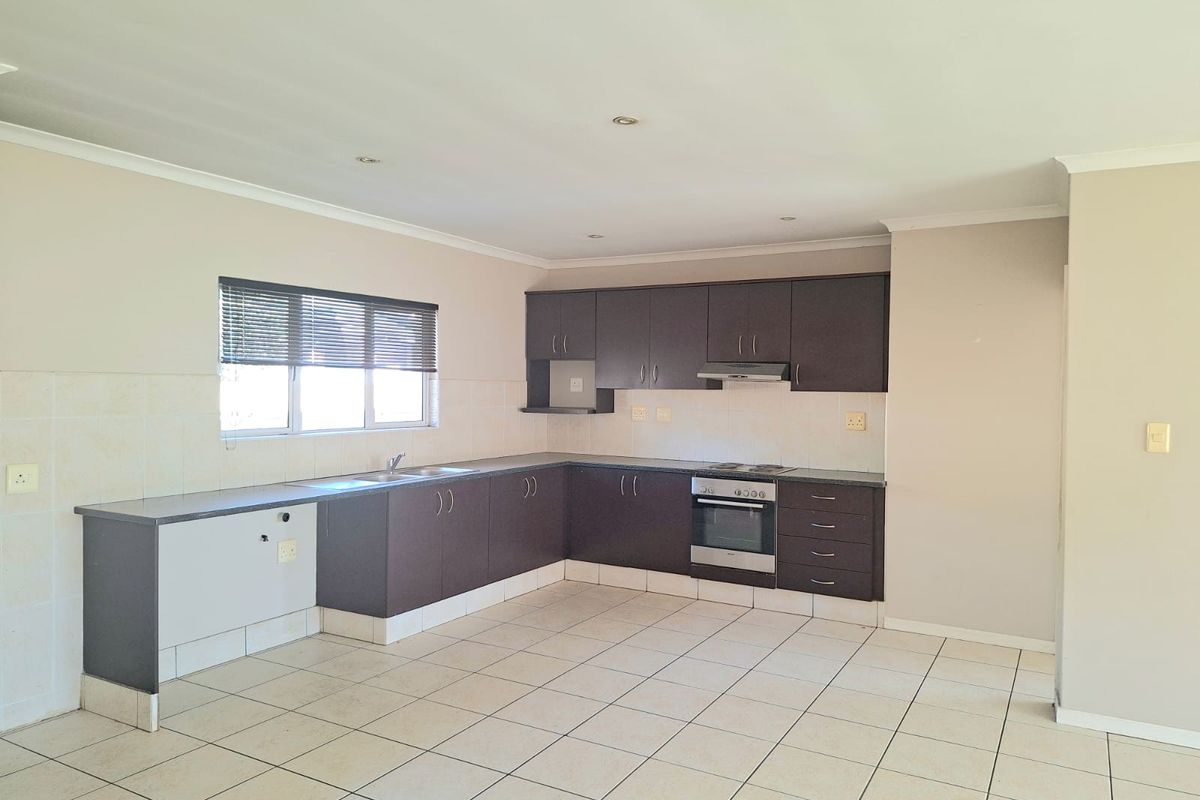 A functional kitchen featuring dark cabinetry, built-in oven and hob, tiled flooring, and a neutral color palette, ready for personalization.